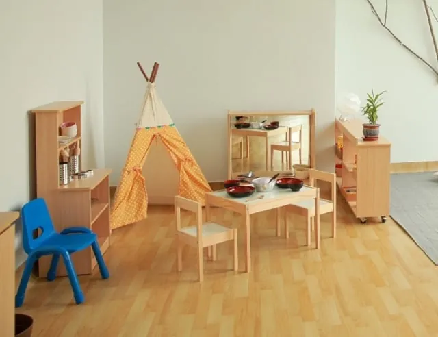 Preschool classroom with a play tent, child-size table and wooden shelves
