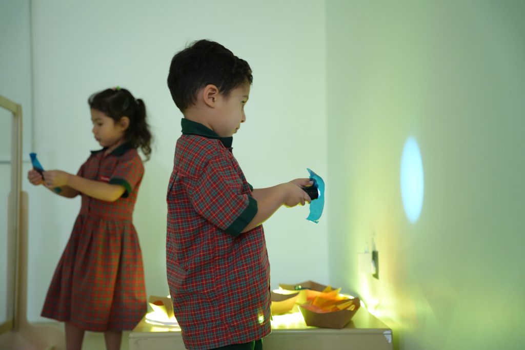Two preschool children exploring light and shadow with coloured filters