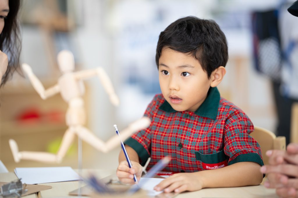 Preschool child drawing a wooden artist’s figure from observation