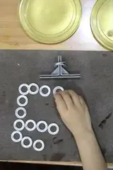 Child arranging bottle caps into a pattern on a mat